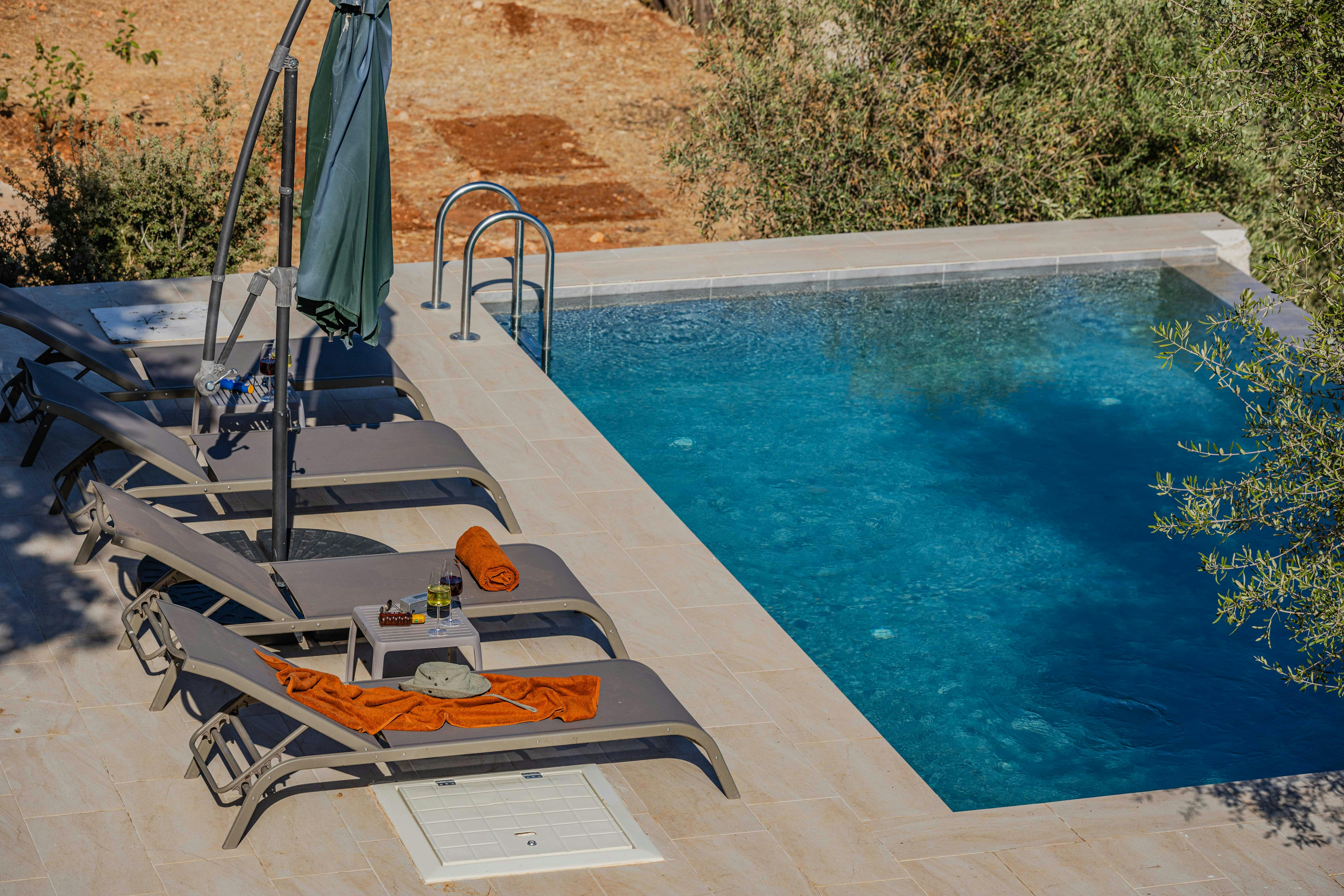 Créez votre oasis de bien-être avec cette piscine béton à débordement, harmonie parfaite entre eau turquoise et plage dallée beige