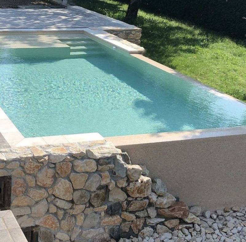 Un design aérien pour cette piscine béton armé sur pilotis, offrant une vue panoramique et une intégration architecturale de prestige.