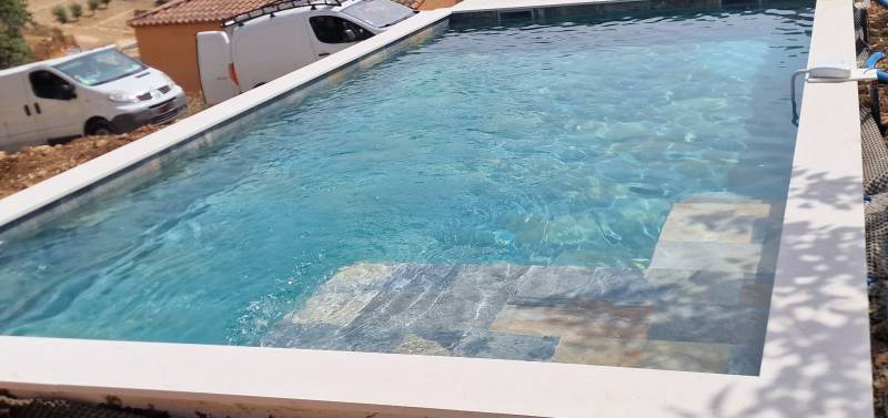 Piscine béton miroir bleu avec plage en carrelage