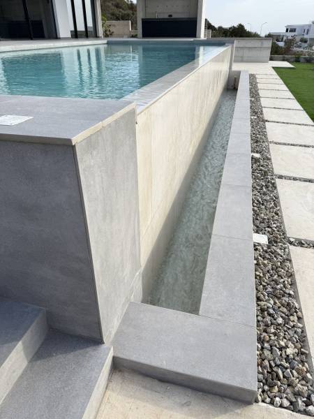 Design épuré et finitions de luxe pour ce bassin en piscine béton armé dont le débordement apporte une sérénité visuelle incomparable.