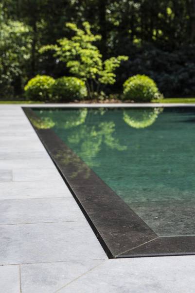 Détail technique du débordement d'une piscine miroir Batibloc sur terrasse épurée.