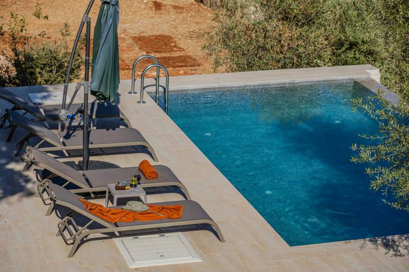 Créez votre oasis de bien-être avec cette piscine béton à débordement, harmonie parfaite entre eau turquoise et plage dallée beige